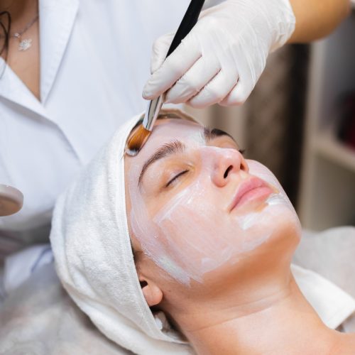 beautician-with-brush-applies-white-moisturizing-mask-face-young-girl-client-spa-beauty-salon (1)