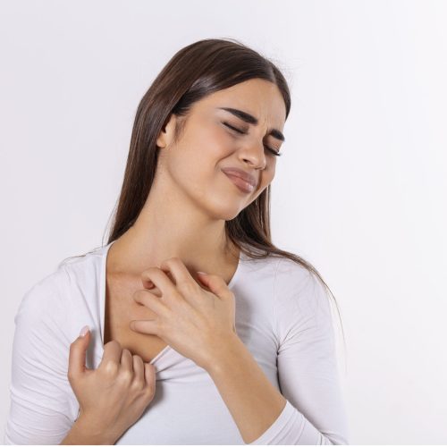 Young woman scratching her neck due to itching on a gray background. Female has an itching neck. The concept of allergy symptoms and healthcare